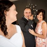 Photo of the bride with her emotional parents in the back ground