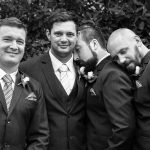 Photograph of groomsmen being affectionate by leaning on each others shoulder