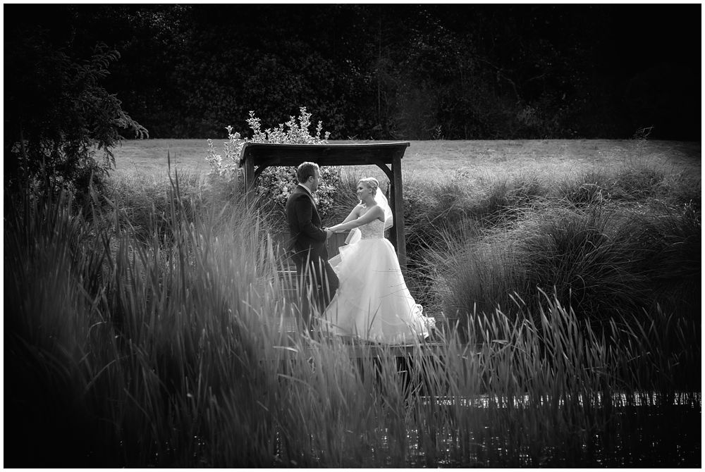 Bride and Groom standing across pond at Flaxton Manor