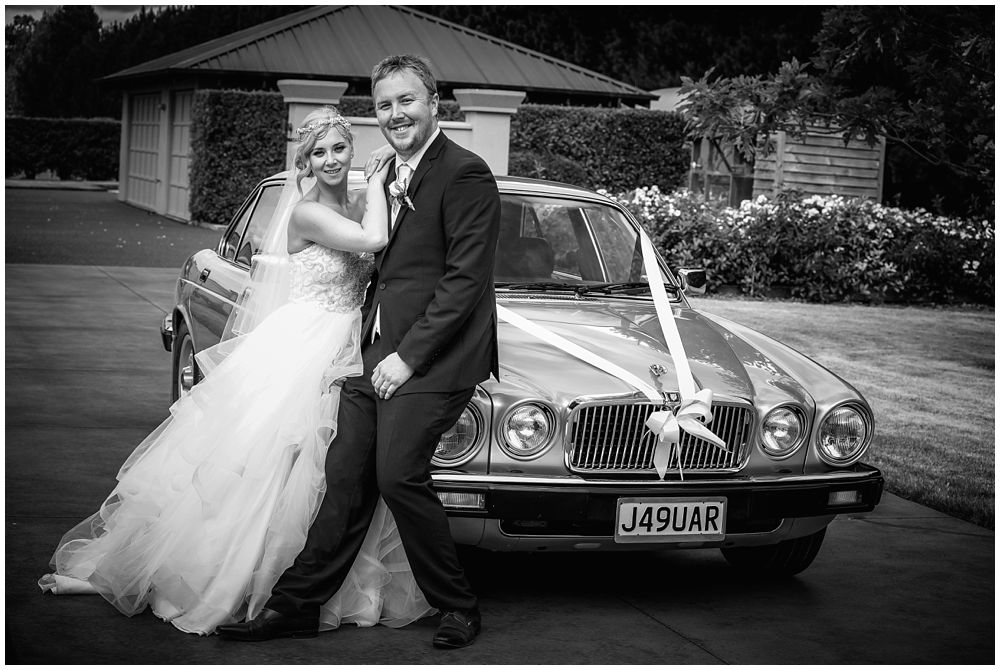 Groom and bride leaning on the bridal car at Fixation Manor