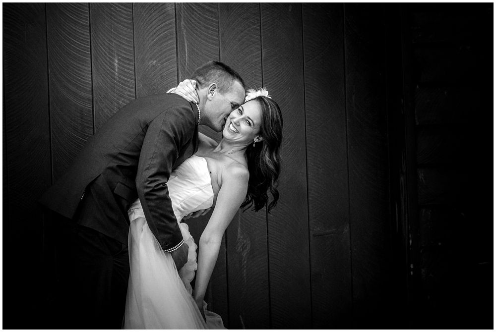 Bride-groom kissing infant of barn door