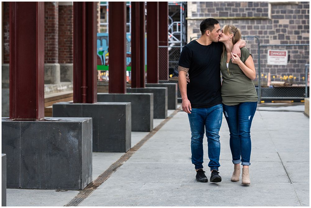 engaged couple kissing while walking