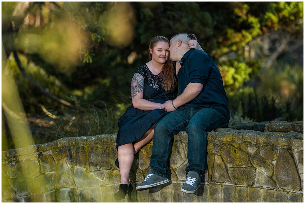 Couple sitting and kissing on bridge