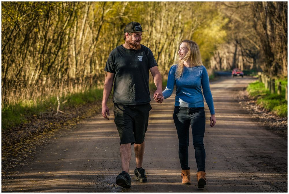 engaged couple walking on dirt road