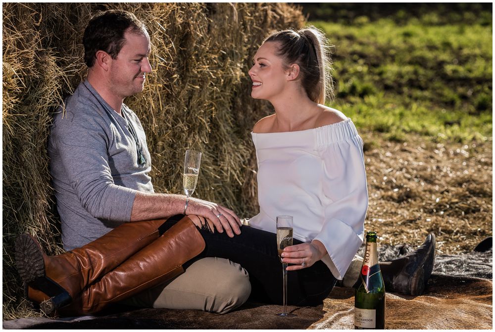 engaged couple sitting on cow hide and drinking wine