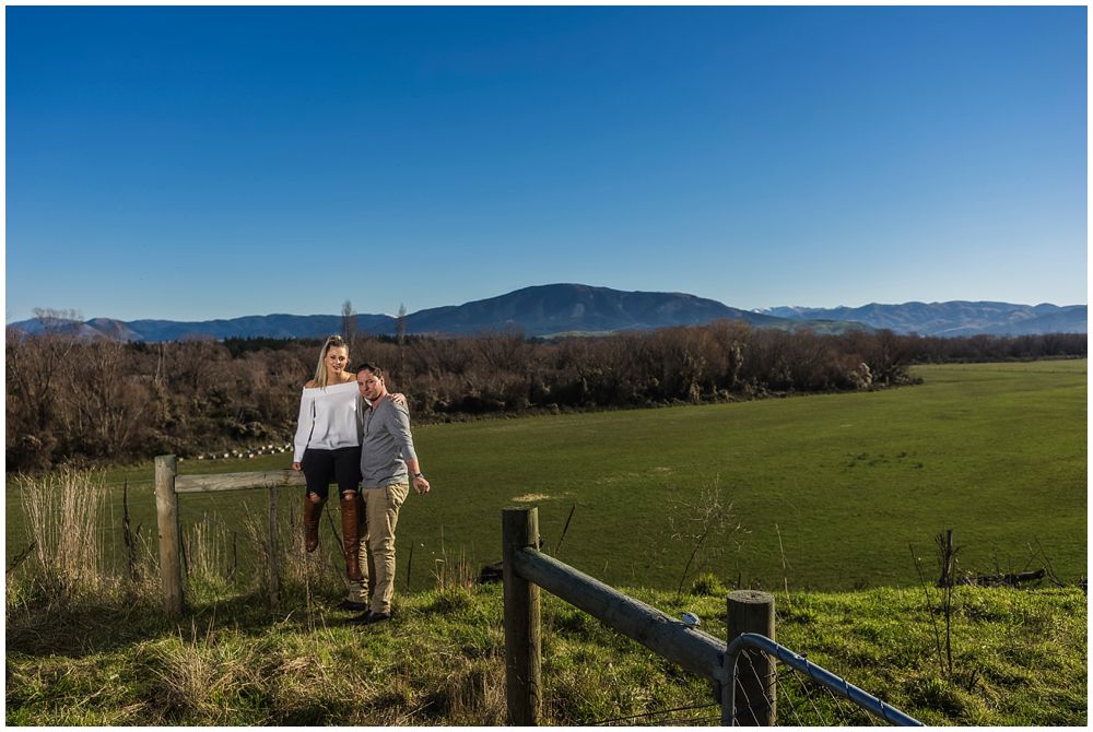 engaged couple standing in front of farm vista view