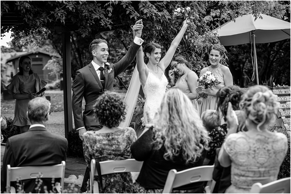 black and white photo of bride and groom lifting thier hands up in the air ccelebrating their marriage